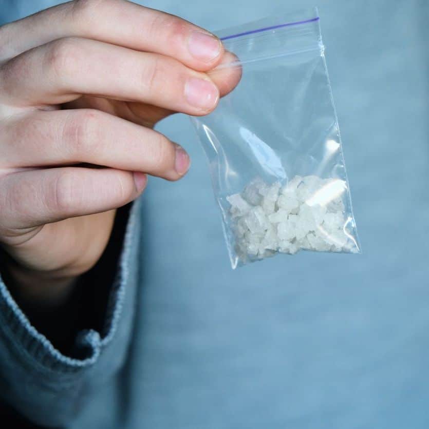 hand holds packet with white narcotic - cocaine, meth or another drug